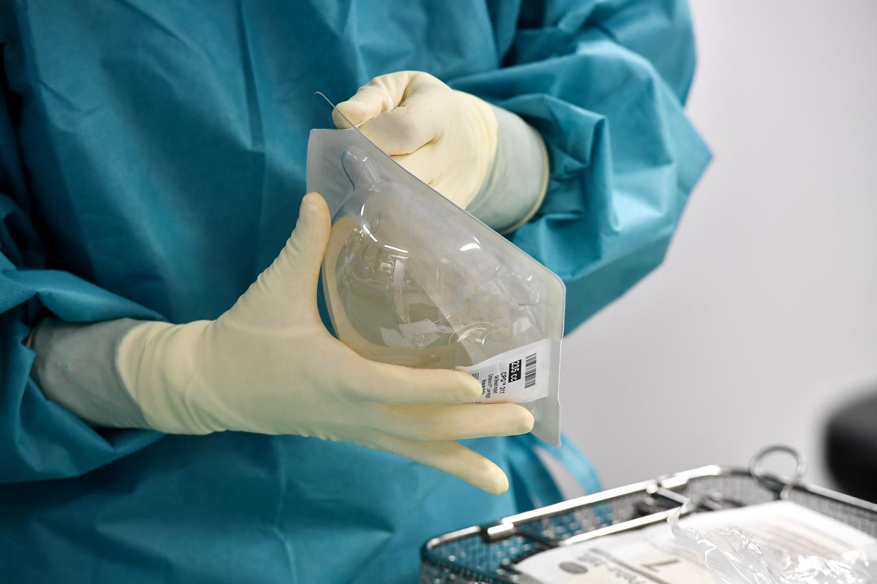 Eine OP-Schwester öffnet die Verpackung eines Brust-Silikonimplantates.